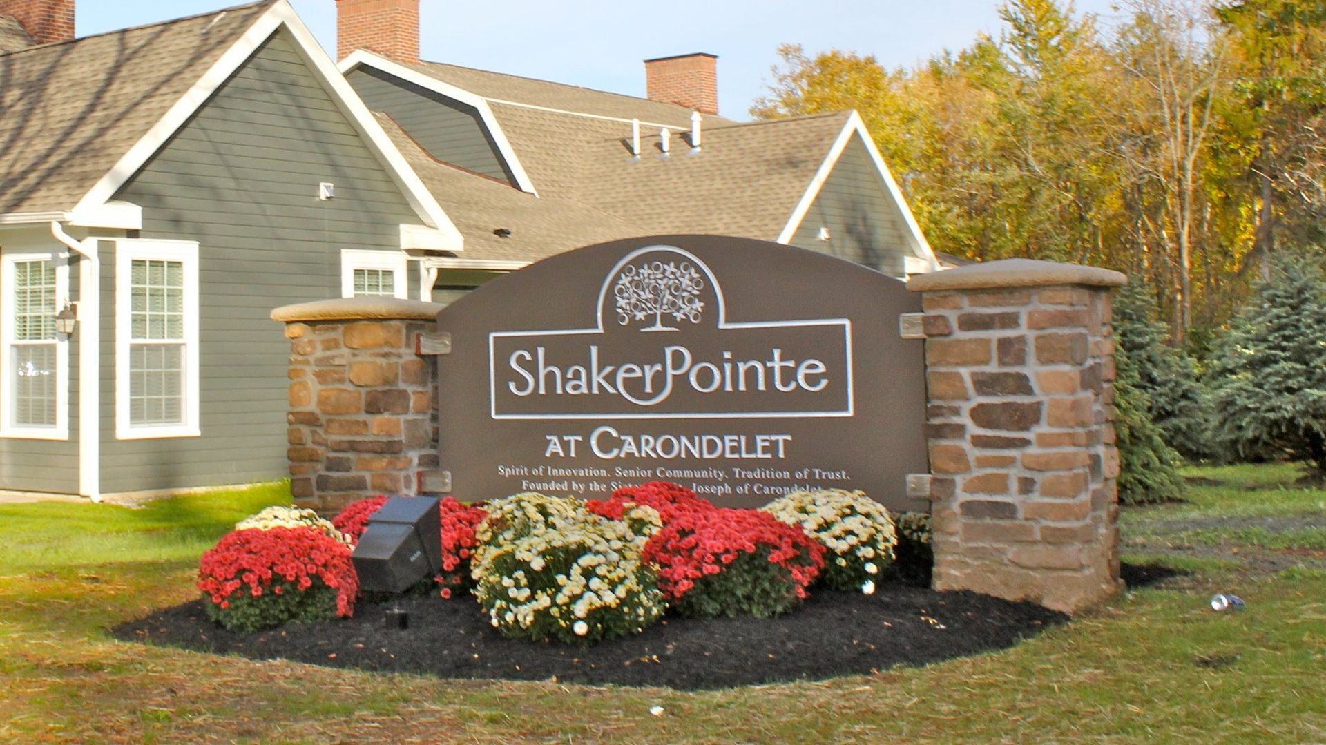 Entrance sign of Shaker Pointe at Carondelet surrounded by flowers and greenery.