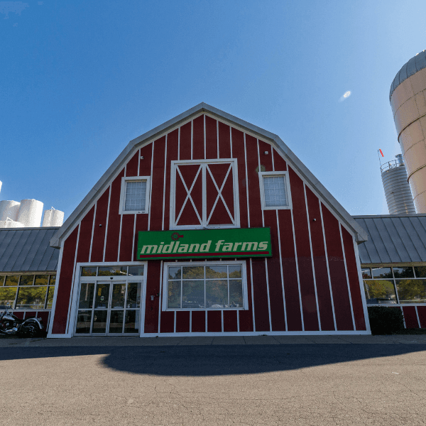 Front view of Midland Farms building with a red barn-style facade and large green sign.