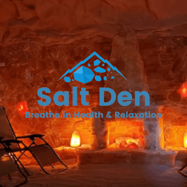 Salt Den logo over a cozy salt cave interior with calming orange lights and lounge chairs for relaxation.